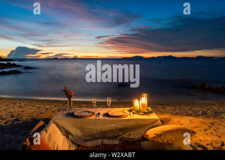 Romantisches Abendessen Tabelle neben dem Strand im Sonnenuntergang Dämmerung an Munnok Island, Thailand. Stockfoto