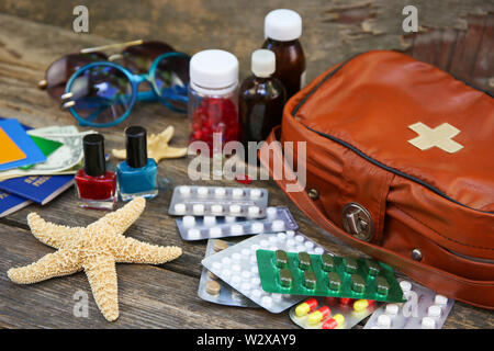 Sommer der Frauen Strand Zubehör für Ihr Meer Urlaub und Erste Hilfe Kit im alten Holz- Hintergrund. Konzept der Medikation in Reise erforderlich. Ansicht von oben. Stockfoto