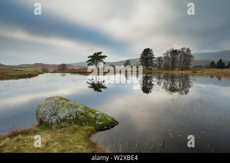 Wunderschöne Landschaft Bild von Moody Sturmwolken über Kelly Halle Tarn in Lake District im späten Herbst am Nachmittag Stockfoto
