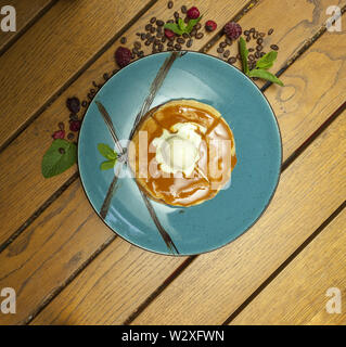 Pfannkuchen mit Eis in blauen Platte auf hölzernen Tisch Stockfoto