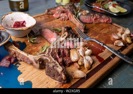 Nach dem Essen über Knochen gelassen werden. Übrig gebliebene Fleisch am Knochen witg gegrillter Knoblauch auf Holzbrett Stockfoto