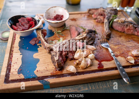 Nach dem Essen über Knochen gelassen werden. Übrig gebliebene Fleisch am Knochen witg gegrillter Knoblauch auf Holzbrett Stockfoto