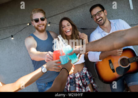 Junge Freunde Spaß an eine Dachterrasse mit Party, Gitarre spielen, Singen, Tanzen und Trinken Stockfoto