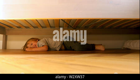 Kind auf der Suche nach etwas unter dem Bett. Stockfoto