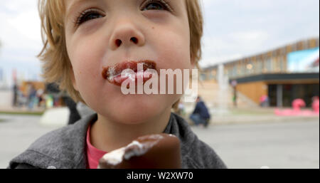 Glückliches Kind trinkt Milch aus einem Becher Stockfoto