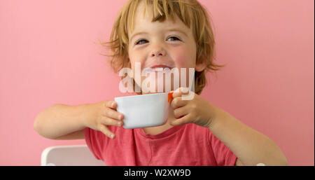 Glückliches Kind trinkt Milch aus einem Becher Stockfoto