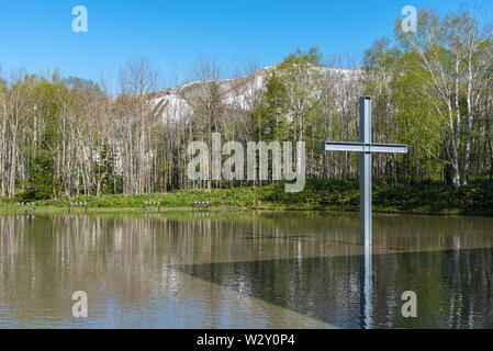 Kreuz auf dem Wasser mit einer umgekehrten Reflexion in einer wunderschönen Natur Wald Berg Hintergrund Stockfoto