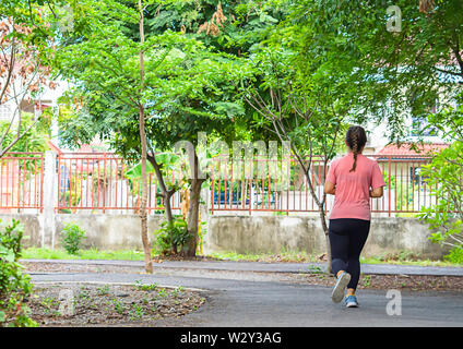 Asiatische Frauen sind Joggen im Park Hintergrund Baum. Stockfoto