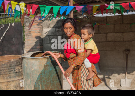 Frau Sammeln von Wasser mit einem Kind auf dem Rücken Stockfoto