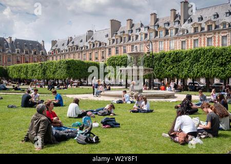 Paris, Frankreich, 25. Mai 2019: Place des Vosges. Menschen entspannend auf den grünen Rasen der berühmten Place des Vosges - älteste geplante Platz im Viertel Marais. Stockfoto