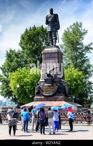 Russland, Irkutsk - Juli 6, 2019: Touristen mit Sonnenschirmen Blick auf das Denkmal für Alexander III. Allrussischen Kaiser Stockfoto