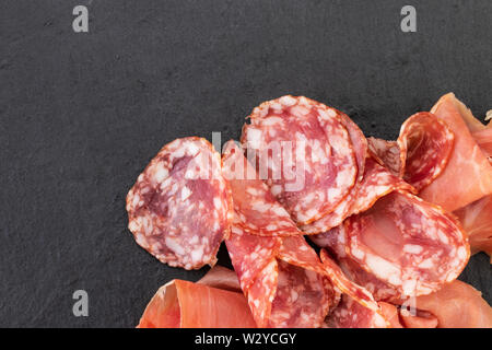 Italienische Prosciutto Crudo oder spanischen Schinken und Würstchen. Rohen Schinken auf Stein Schneidebrett. Stockfoto