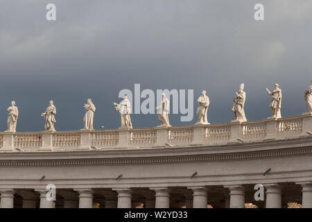 Italien, Vatikanstadt - 18 April 2017: der Blick auf eine Gruppe von Statuen von Peter's Square Kolonnade mit regnerischen Wolken im Hintergrund Am 18. April 2017, Vatica Stockfoto