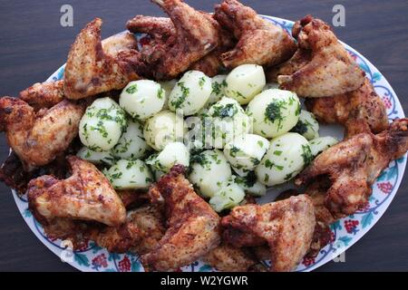 Crunchy Chicken Wings mit Baby Kartoffeln und Petersilie Stockfoto