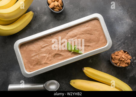 Banane Schokolade hausgemachtes Eis in Container mit Kaffeebohnen auf Schwarz. Ansicht von oben. Stockfoto