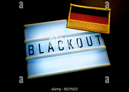 Das Wort Blackout auf einer beleuchteten Panel und Flagge von Deutschland, Stromausfall Stockfoto