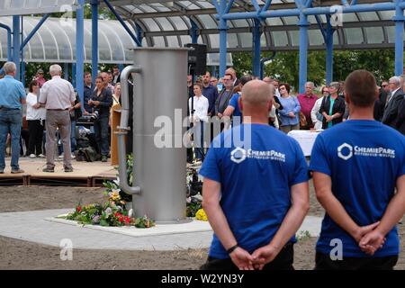 Bitterfeld Wolfen, Deutschland. 11. Juli, 2019. Die Teilnehmer der Gedenkfeier stehen an einem Denkmal in der Chemischen Park. Eine Stele erinnert an die Opfer der chemischen Unfall vom 11.07.1968, bei der 40 Menschen starben und mehr als 240 wurden verletzt. Credit: Sebastian Willnow/dpa-Zentralbild/ZB/dpa/Alamy leben Nachrichten Stockfoto