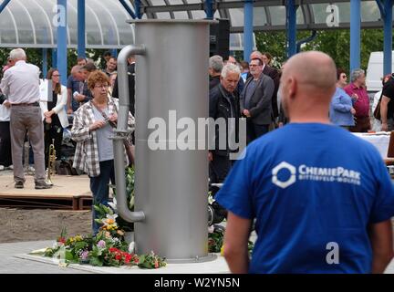 Bitterfeld Wolfen, Deutschland. 11. Juli, 2019. Die Teilnehmer der Gedenkfeier stehen an einem Denkmal in der Chemischen Park. Eine Stele erinnert an die Opfer der chemischen Unfall vom 11.07.1968, bei der 40 Menschen starben und mehr als 240 wurden verletzt. Credit: Sebastian Willnow/dpa-Zentralbild/ZB/dpa/Alamy leben Nachrichten Stockfoto