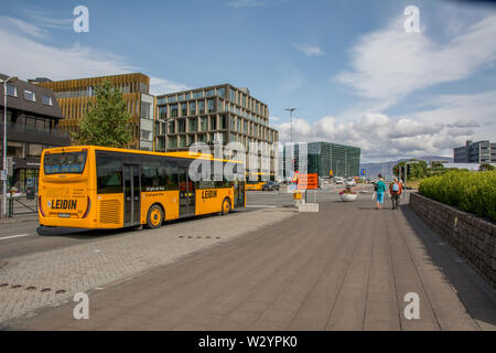 Island, Reykjavik, Juli 2019: Blick auf die Laekjargata, Harpa Museum im Hintergrund, gelb Besta Leidin öffentliche Verkehrsmittel Bus im Vordergrund Stockfoto