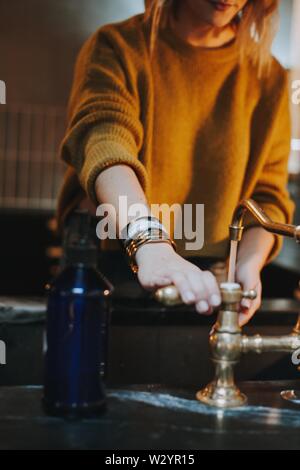 Frau in einem warmen Pullover mit der Hand auf der Kurbel waschen ihre Hände Stockfoto