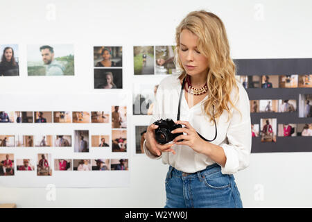 Weibliche Graphic Designer überprüfung Fotos auf digitale Kamera im Büro Stockfoto