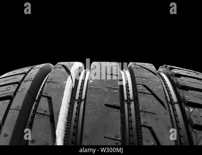 Studio Schuß aus einer Reihe von Sommer PKW-Reifen auf schwarzem Hintergrund. Reifen Hintergrund stack. Autoreifen protector hautnah. Schwarzer Gummireifen. Nagelneues Auto Tir Stockfoto