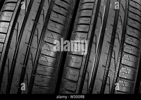 Studio Schuß aus einer Reihe von Sommer PKW-Reifen auf schwarzem Hintergrund. Reifen Hintergrund stack. Autoreifen protector hautnah. Schwarzer Gummireifen. Nagelneues Auto Tir Stockfoto