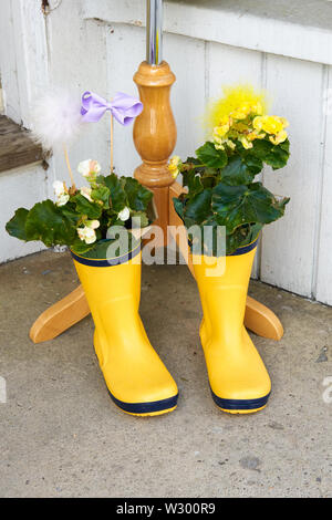 Childs leuchtend gelben Gummi regen Stiefel als Blume Pflanzmaschinen sitzen auf dem Bürgersteig mit einem Lavendel ribbon Dekoration verwendet werden Stockfoto