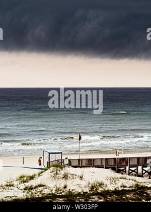 Gulf Shores, AL USA - 05/09/2019 - Sturmwolken über Strand und Holzsteg Stockfoto