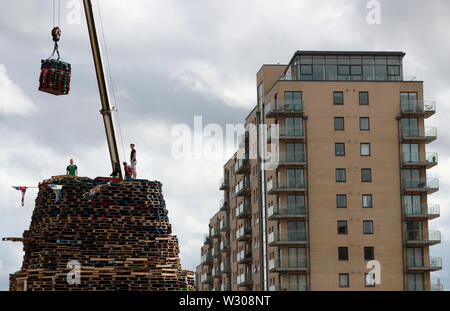 Bonfire Erbauer in der Sandy Row Bereich von Belfast als Gebäude weiterhin auf die loyalistischen Lagerfeuer, die sich traditionell auf die elfte Nacht beleuchtet werden, die in der Zwölften Gedenkfeiern zu etablieren. Stockfoto