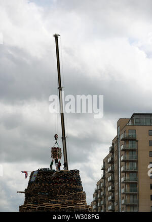 Bonfire Erbauer in der Sandy Row Bereich von Belfast als Gebäude weiterhin auf die loyalistischen Lagerfeuer, die sich traditionell auf die elfte Nacht beleuchtet werden, die in der Zwölften Gedenkfeiern zu etablieren. Stockfoto