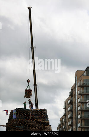 Bonfire Erbauer in der Sandy Row Bereich von Belfast als Gebäude weiterhin auf die loyalistischen Lagerfeuer, die sich traditionell auf die elfte Nacht beleuchtet werden, die in der Zwölften Gedenkfeiern zu etablieren. Stockfoto