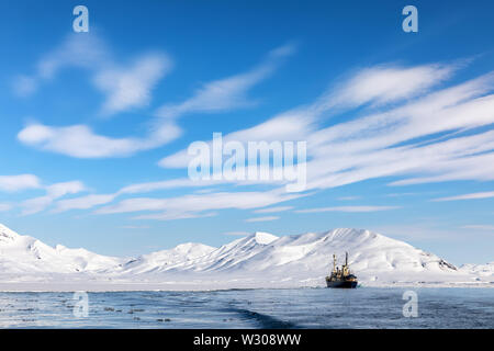 Boot auf den Fjorden von Svalbard, ein Norwegisches Archipel zwischen dem norwegischen Festland und dem Nordpol, mit schneebedeckten Bergen und blauem Himmel. Stockfoto