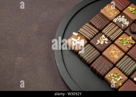 Pralinen Vielfalt in schwarz Fach auf braunem Hintergrund Stockfoto