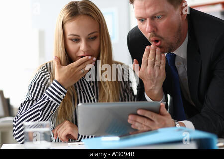 Portrait von schockiert, Frau und Mann, die Hände in den Mund mit großer Verwunderung. Hübsche Frauen in gestreifte Bluse etwas zu lesen mit bärtigen Mann Co Stockfoto