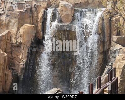 Wasser ergiesst sich Felsen in einem angelegten Garten Stockfoto