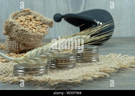 Aus einem Stück von Weizen zur Festlegung über Stapel von Silbermünzen, hessische Sack von Korn und kleinen Rahmen Geldbeutel im Hintergrund, Körner Markt und Preise Konzept Stockfoto