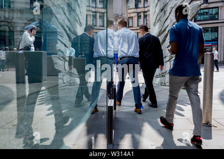 Finanzindustrie Geschäftsleute Spaziergang, vorbei an der Skulptur Stadt Flügel auf Threadneedle Street in der City von London, das Finanzviertel der Hauptstadt (aka der Square Mile), am 11. Juli 2019 in London, England. Stadt Flügel wird von dem Künstler Christopher Le Brun. Die zehn Meter hohe Bronzeskulptur wird von dem Präsidenten der Königlichen Akademie der Künste, Christopher Le Brun, von hammerson im Jahr 2009 in Betrieb genommen. Es wird "die Stadt Flügel" und wurde von der Morris Sänger Kunst Gründer, angeblich der älteste Gießerei in die Welt geworfen wurde. Stockfoto