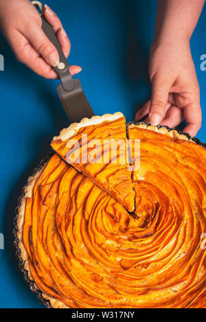 Frau Hände unter einer Schicht von Kartoffel Torte aus einem Fach frisch gebackene Herbst pie. Traditionelle American Pie mit Kruste. Scheibe der Sweet potato pie. Stockfoto