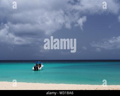 Verankert/Aussenborder Schnellboot floating in den Untiefen am türkisfarbenen Wasser der Karibik, Meads Bay, Anguilla, BWI. Stockfoto