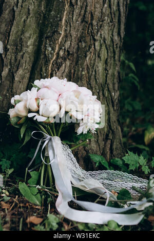 Nahaufnahme eines schönen und stilvollen Brautstrauß aus weißen und rosa Pfingstrosen auf Holz- Hintergrund. Stockfoto