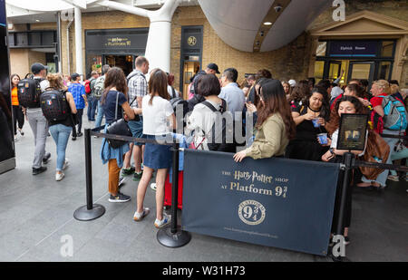 Harry Potter Fans Warteschlange in einer Warteschlange außerhalb der Kings Cross Station Harry Potter Shop am Bahnsteig 9 3/4, Bahnhof Kings Cross, London, UK Stockfoto