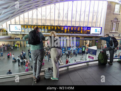 Der Bahnhof Kings Cross London: ein Paar der Passagiere auf die Abfahrt des Zuges aus der Bahnhofshalle suchen, Kings Cross Bahnhof, London UK Stockfoto