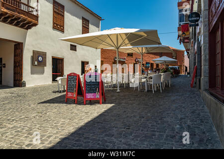 Puerto de la Cruz, Teneriffa, Spanien - Juli 10, 2019: Bunte Häuser und Palmen auf Straßen. Menschen entspannen und Spaß an einem warmen Sommertag. Stockfoto