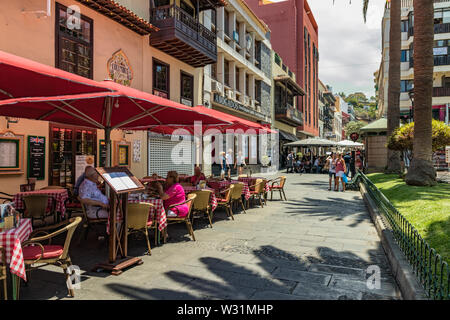 Puerto de la Cruz, Teneriffa, Spanien - Juli 10, 2019: Bunte Häuser und Palmen auf Straßen. Menschen entspannen und Spaß an einem warmen Sommertag. Stockfoto