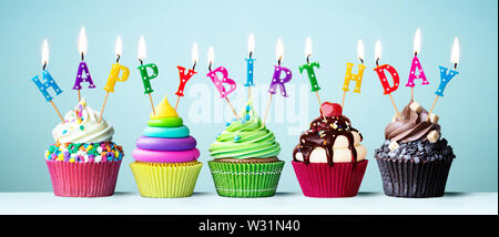 Bunte kleine Kuchen mit Kerzen Rechtschreibung alles Gute zum Geburtstag Stockfoto