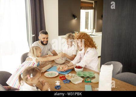 Zeit mit der Familie. Glückliche Familie sitzt um den Tisch, während zusammen kochen begeistert Stockfoto