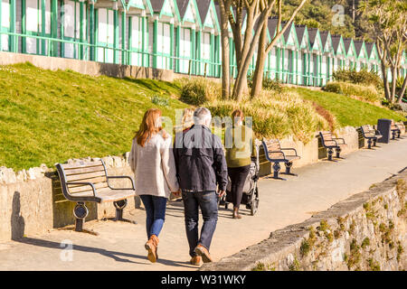 LANGLAND BAY, Gower, WALES - Februar 2019: Mann und Frau gehen Hand in Hand entlang der Promenade im Sonnenschein in Langland Bay auf der Gower Peninsula Stockfoto