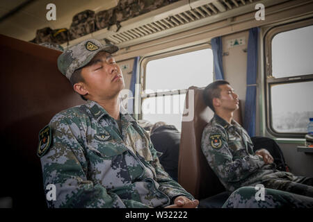 Kashgar, China. 20 Apr, 2019. Zwei chinesische Befreiungsarmee (PLA) Offizier im Ruhezustand auf einem Zug in der Nähe von Kashgar Bahnhof gesunken. Die Provinz Xinjiang im Nordwesten von China gelegen ist, ist es die grösste Provinz in China. Mehrheit der Bevölkerung sind Muslime in Xinjiang. Vor kurzem hat die chinesische Regierung eine massive Sicherheit Durchgreifen in Xinjiang, wo mehr als eine Million ethnischer Uiguren und andere meist muslimischen Minderheiten geglaubt werden in einem Netzwerk von Internierungslager, dass Peking beschreibt als ''berufliche Bildung Zentren' am Lenkrad Leute weg Ziel gehalten zu werden f durchgesetzt Stockfoto