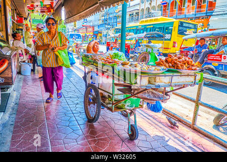 BANGKOK, THAILAND - 22. APRIL 2019: Die schmalen überdachten Gehweg mit großen Handel Trolley mit gebratenen Fisch, Hühnchen und andere Gerichte, am 22. April in B Stockfoto